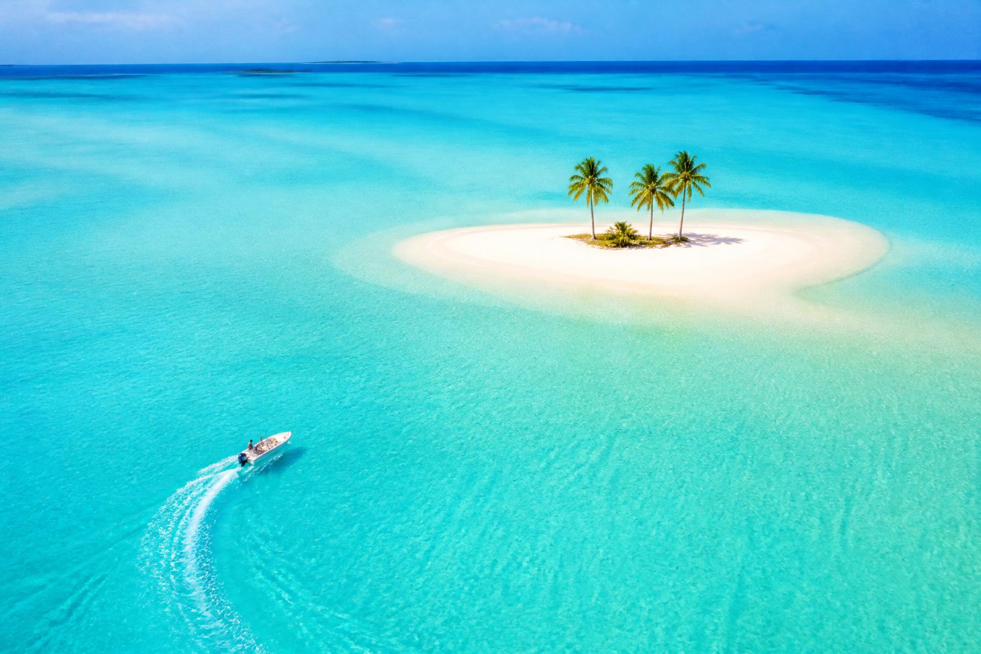 Isla de arena blanca con palmeras en una laguna turquesa cristalina